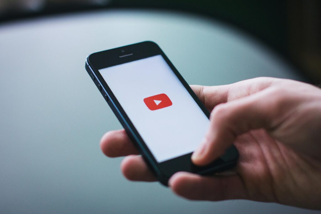 Close-up of a hand holding a smartphone displaying the YouTube app on the screen.